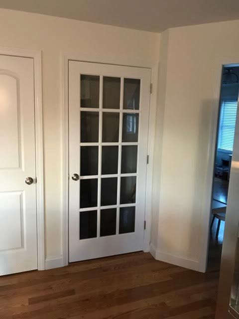 White-framed French door with multiple glass panes, next to a white door and an open doorway.