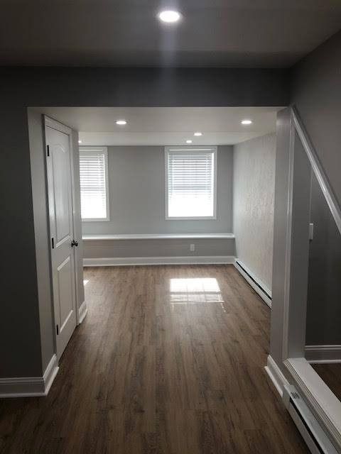 Gray-walled room with wood-look floor; white door and trim; recessed lighting; window bench; sunlight.