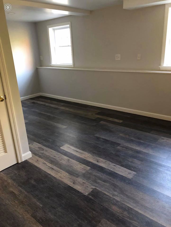 Room with dark wood-look floor and light gray walls; two windows above a low ledge.
