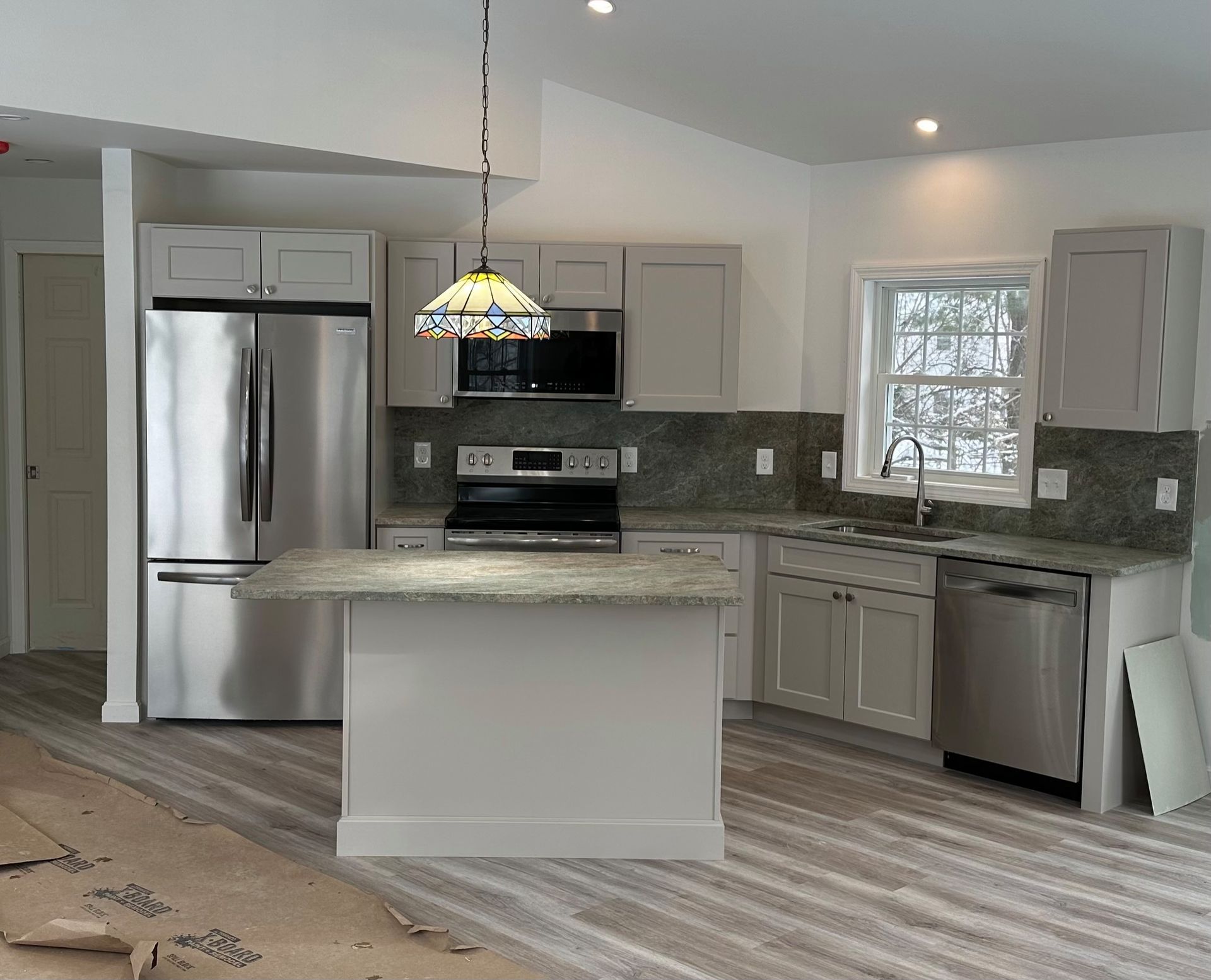 Modern kitchen with stainless steel appliances, gray cabinets, and granite countertops.