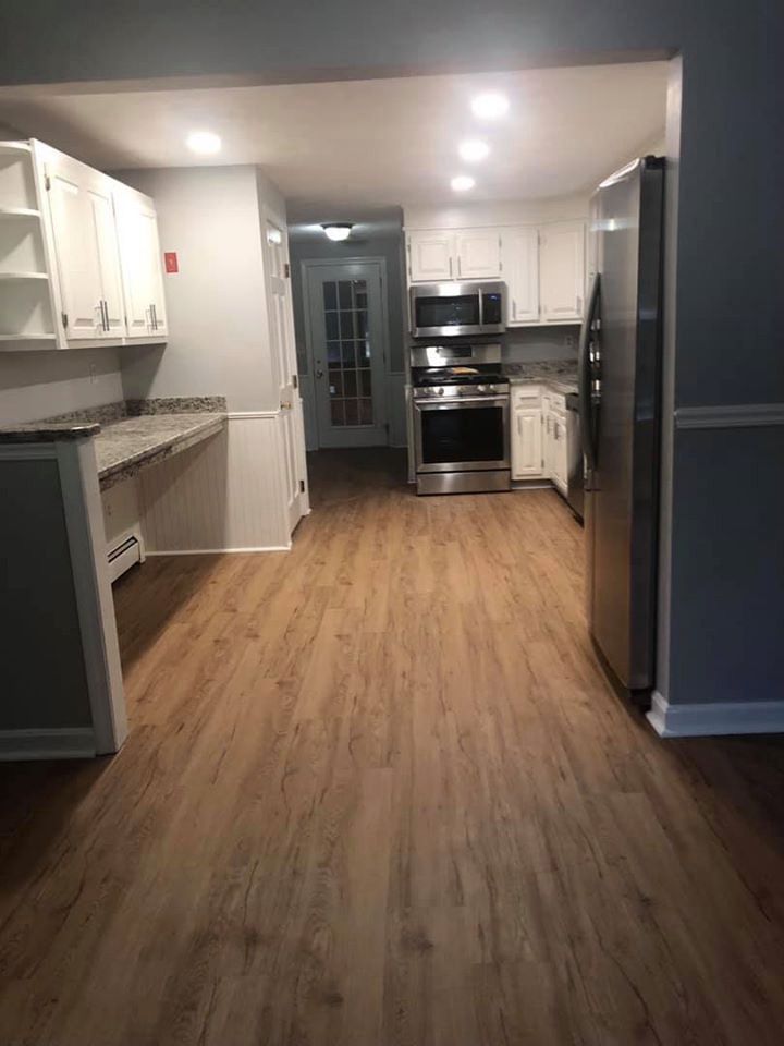 Kitchen with wood-look flooring, white cabinets, stainless steel appliances, and gray walls.