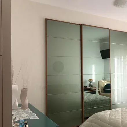 Camera da letto con ante scorrevoli a specchio e letto parzialmente visibile.