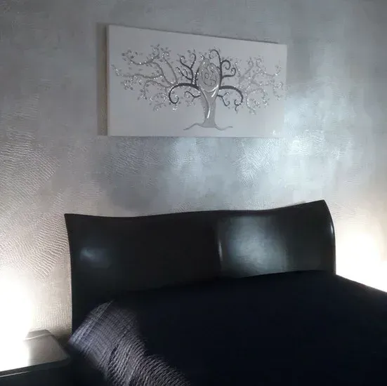 Testiera e letto neri con parete e albero decorati in argento.
