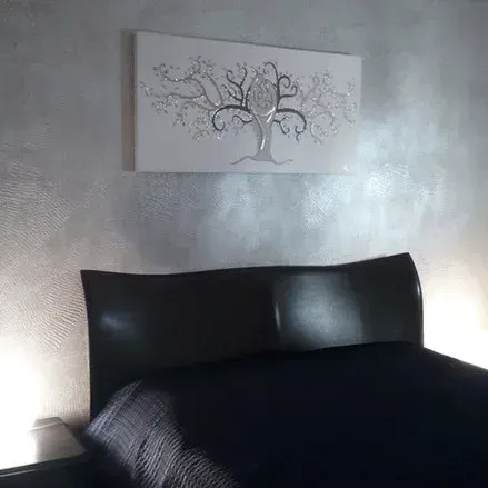 Parete metallica argentata con letto e albero decorativo.