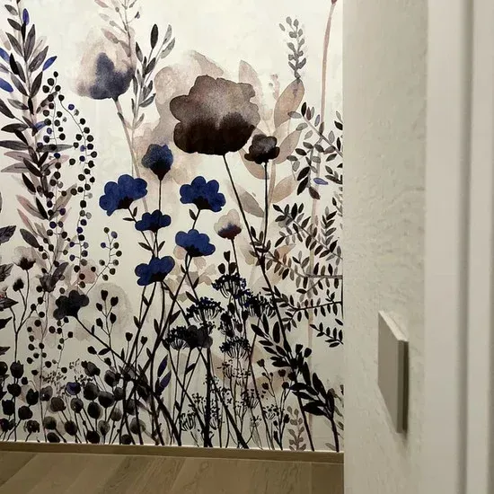 Carta da parati floreale ad acquerello con fiori e fogliame blu e marroni su una parete bianca.