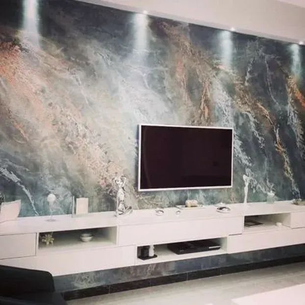 Un soggiorno moderno con una grande TV montata su una parete decorativa in marmo sopra un mobile porta TV bianco.
