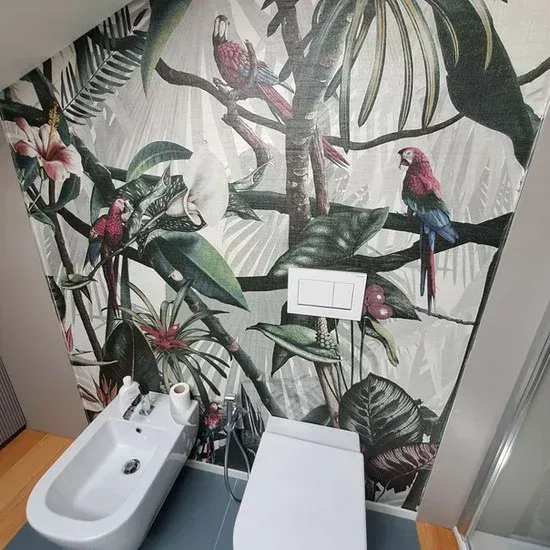 Bagno con carta da parati tropicale raffigurante pappagalli e fogliame, bidet e WC.