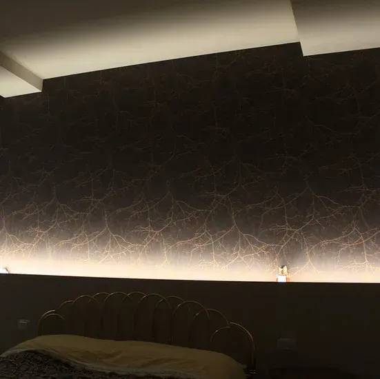 Camera da letto con carta da parati a motivi scuri, letto e illuminazione a strisce.
