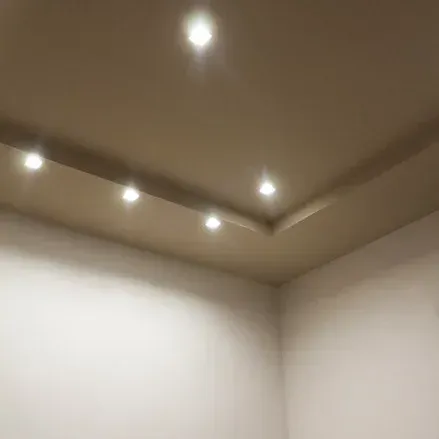 Soffitto beige con luci da incasso in un angolo della stanza, pareti bianche.