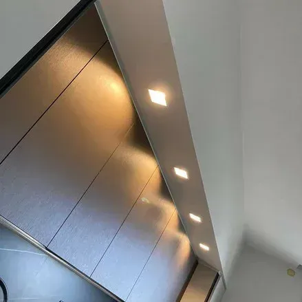 Pannelli murali metallici con luci incassate lungo un soffitto bianco.