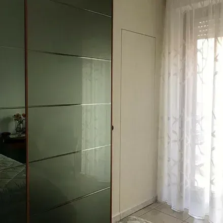 Ante dell'armadio a specchio accanto a una parete con una porta nascosta, vicino a una finestra con tende trasparenti.