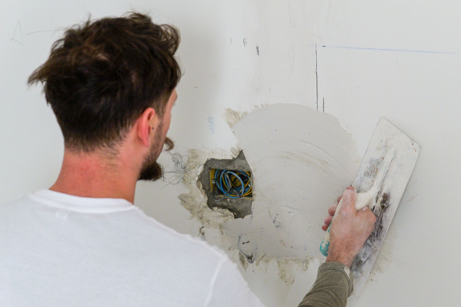 Lussuoso soggiorno: pareti bianche, dettagli dorati, grandi finestre con tende trasparenti, lampadario di cristallo e mobili beige.