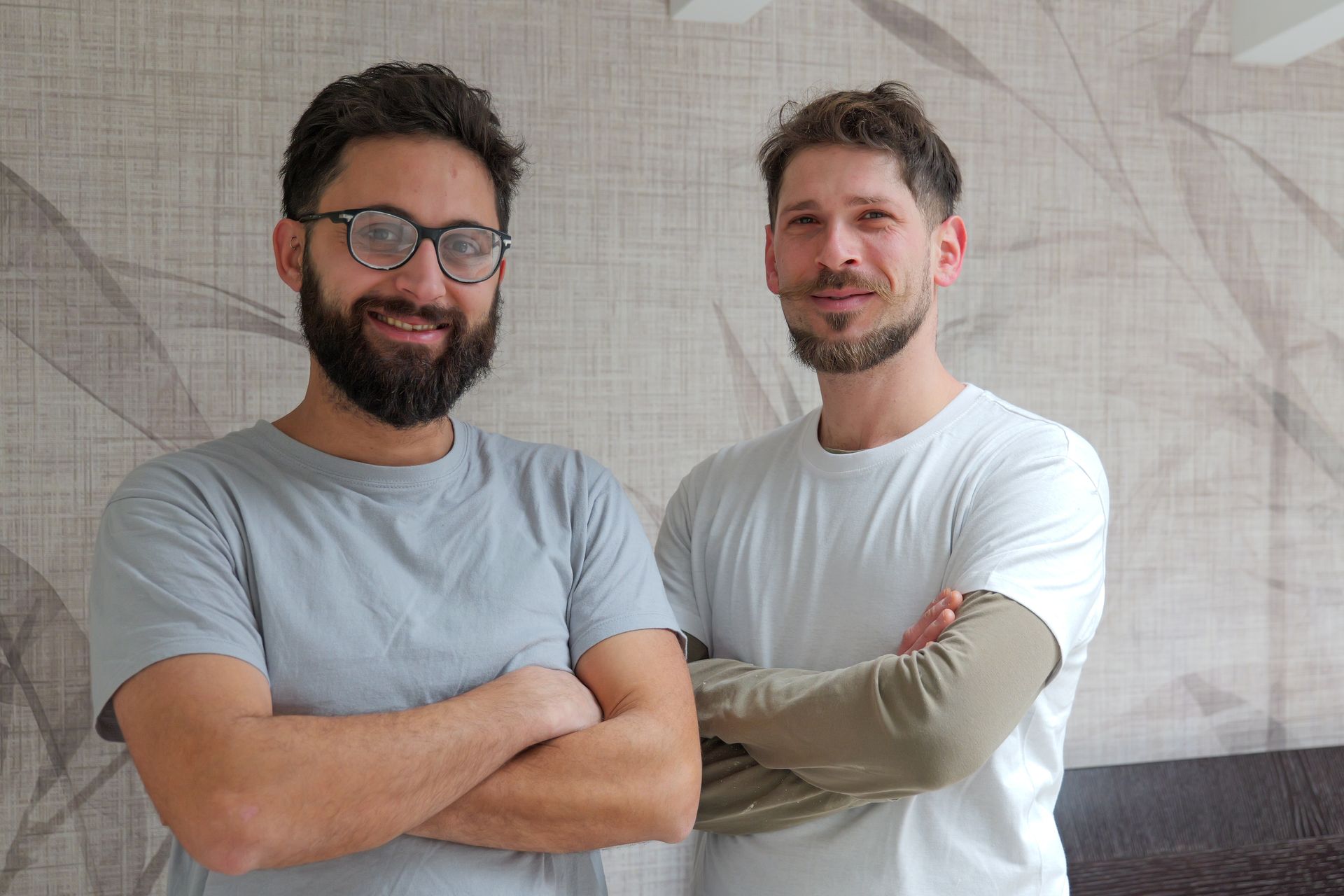 Parete scura con motivo a rami dorati, illuminata da una piccola lampada.