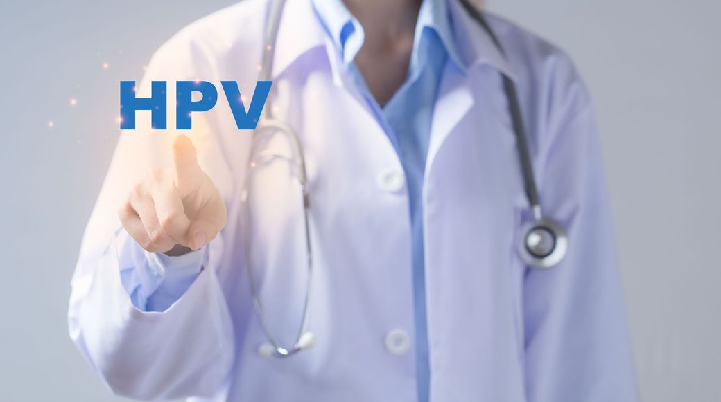 Un medico preme un pulsante su uno schermo su cui è scritto hpv.