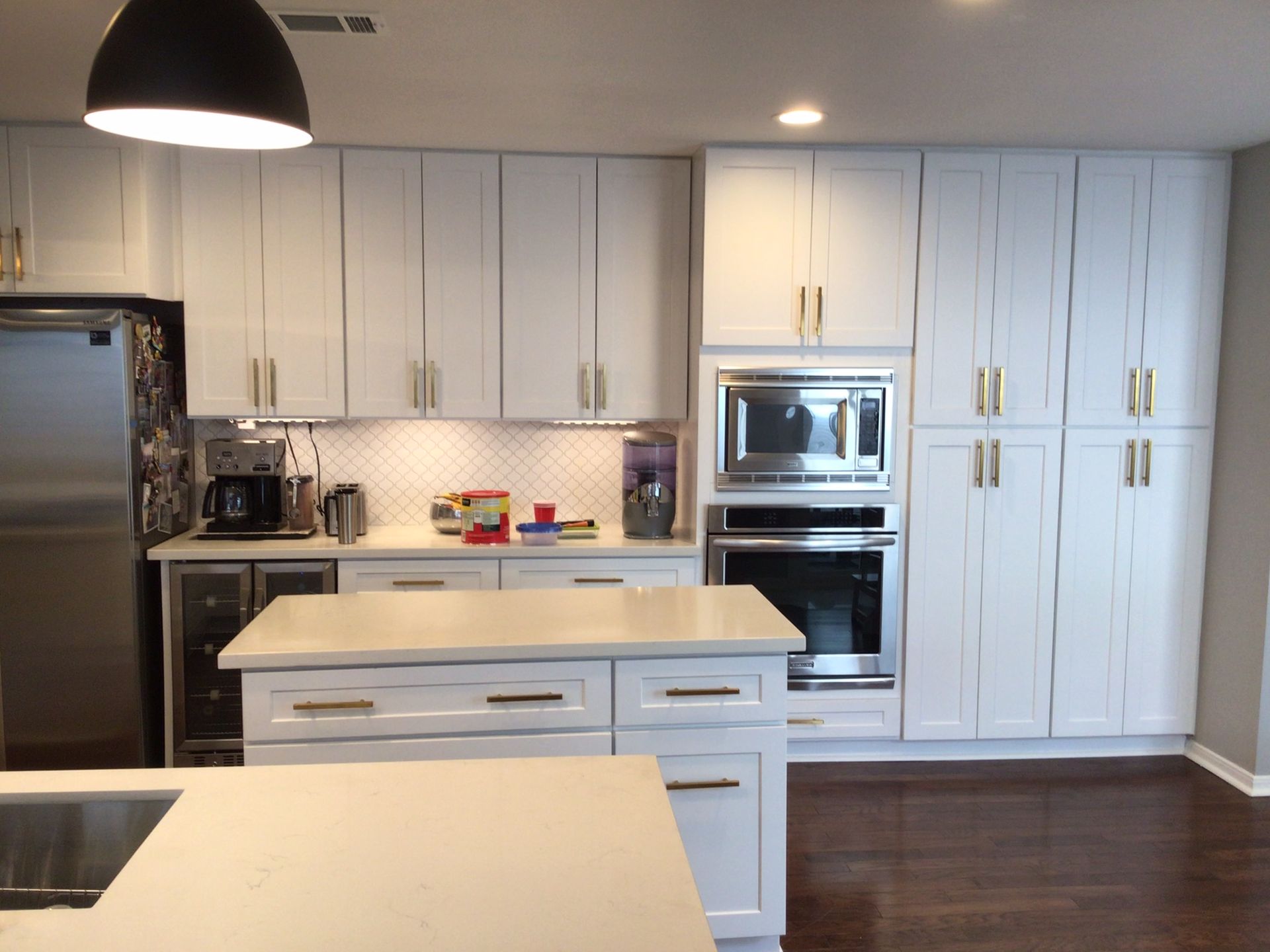 A kitchen with white cabinets and a black hood