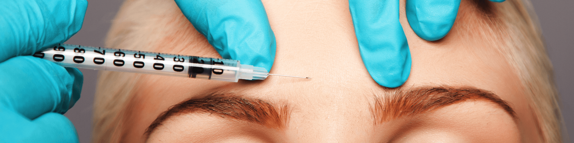 A woman is getting a botox injection in her forehead.