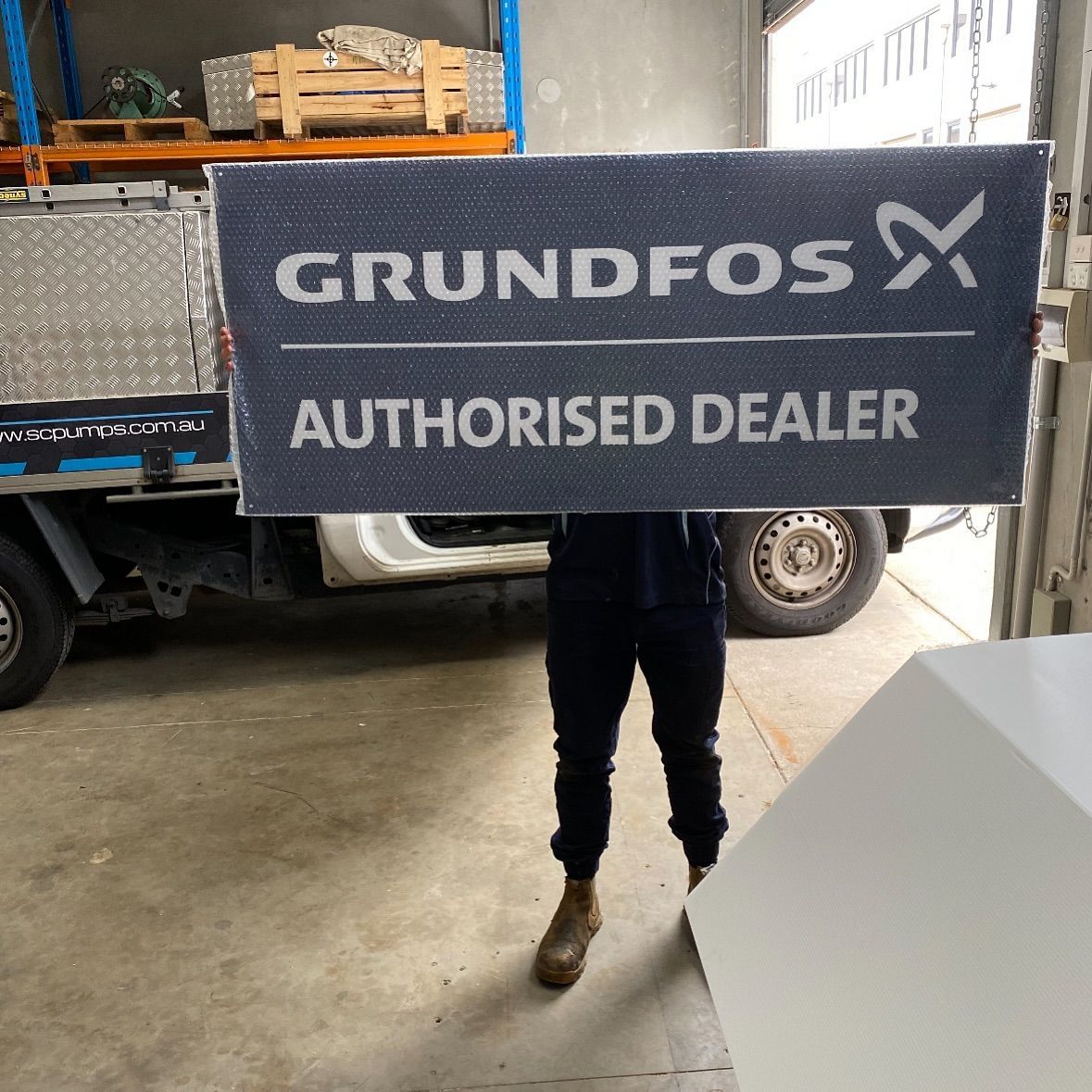 A man is holding a sign that says grundfos authorised dealer
