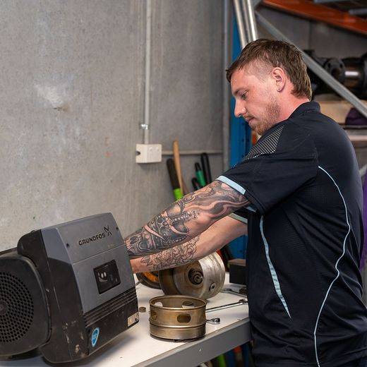 Technician servicing a Grundfos pump control unit during a repair