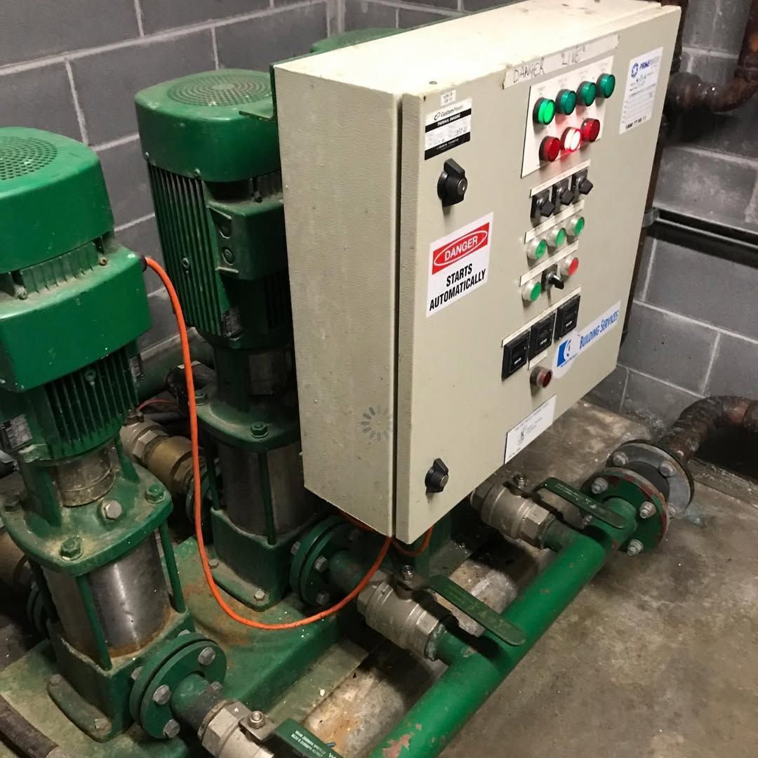 Green water pumps and control panel in an industrial setting.