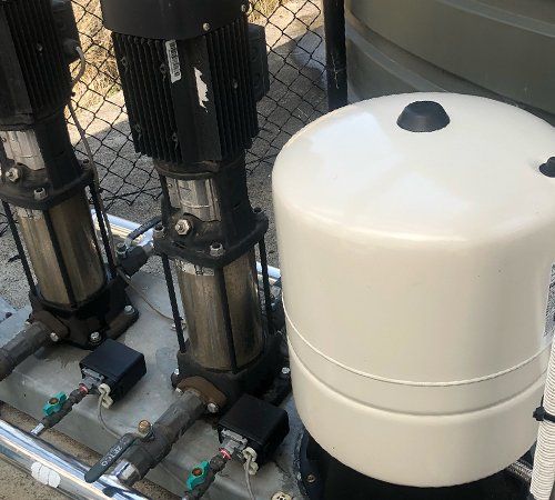 A water pump is sitting next to a white tank.