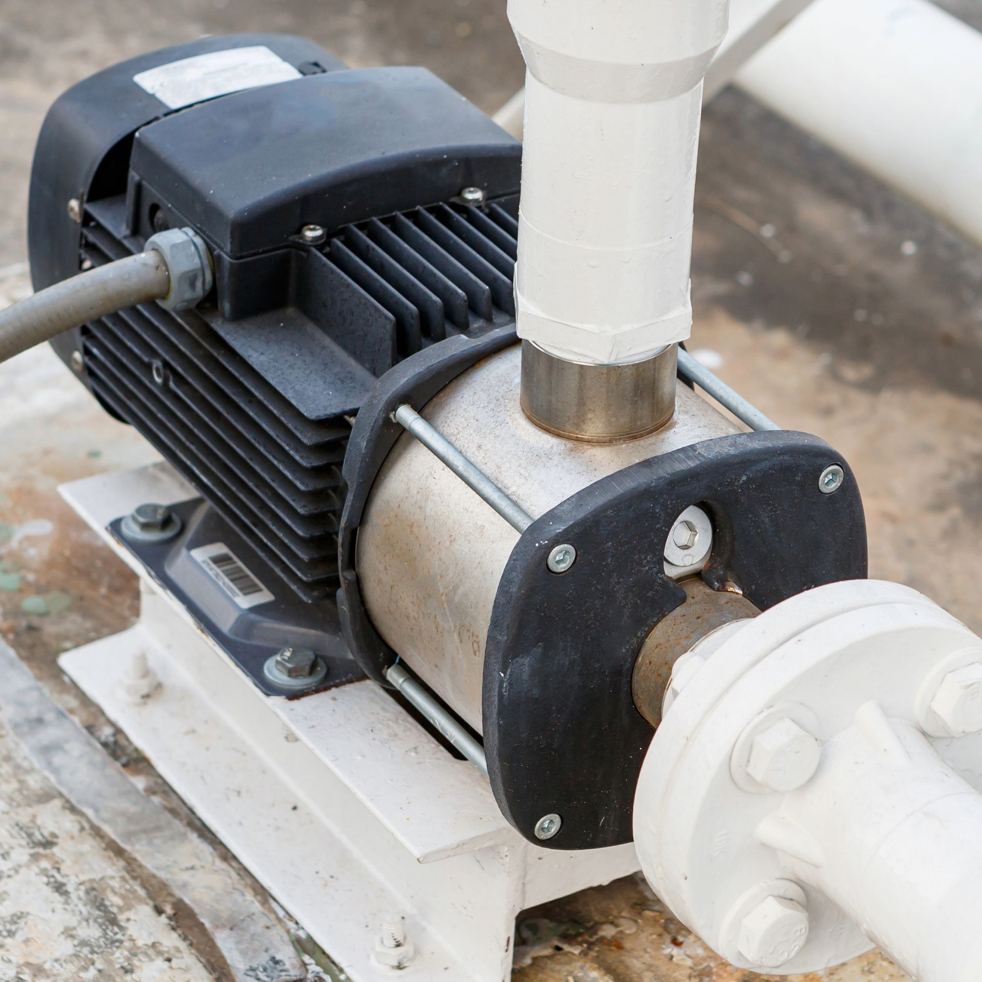Water pump with black motor and white pipes.