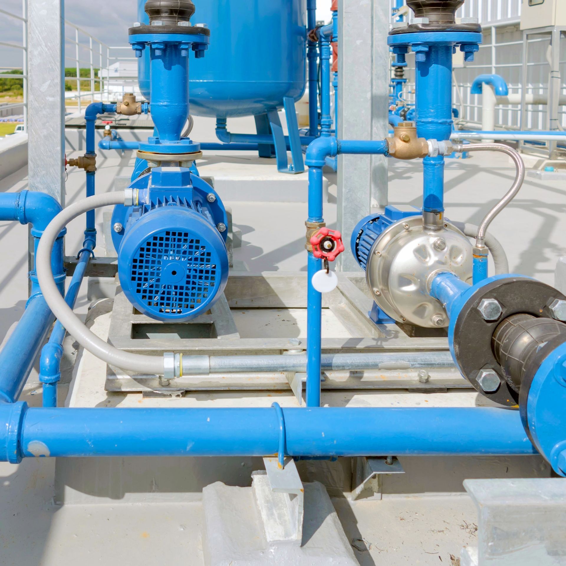 Blue industrial water pumps and pipes on a concrete surface.