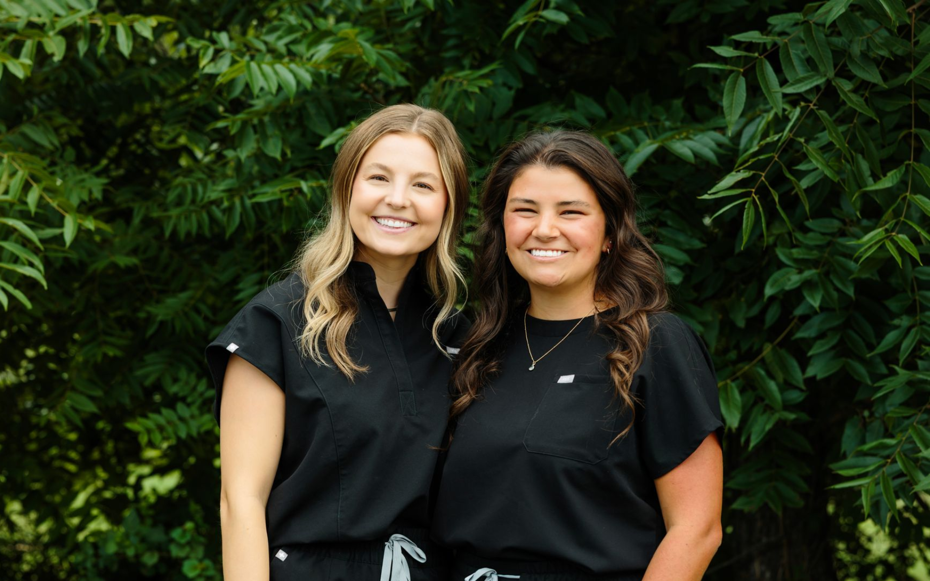 Three dental assistants are posing for a picture in front of a tree.