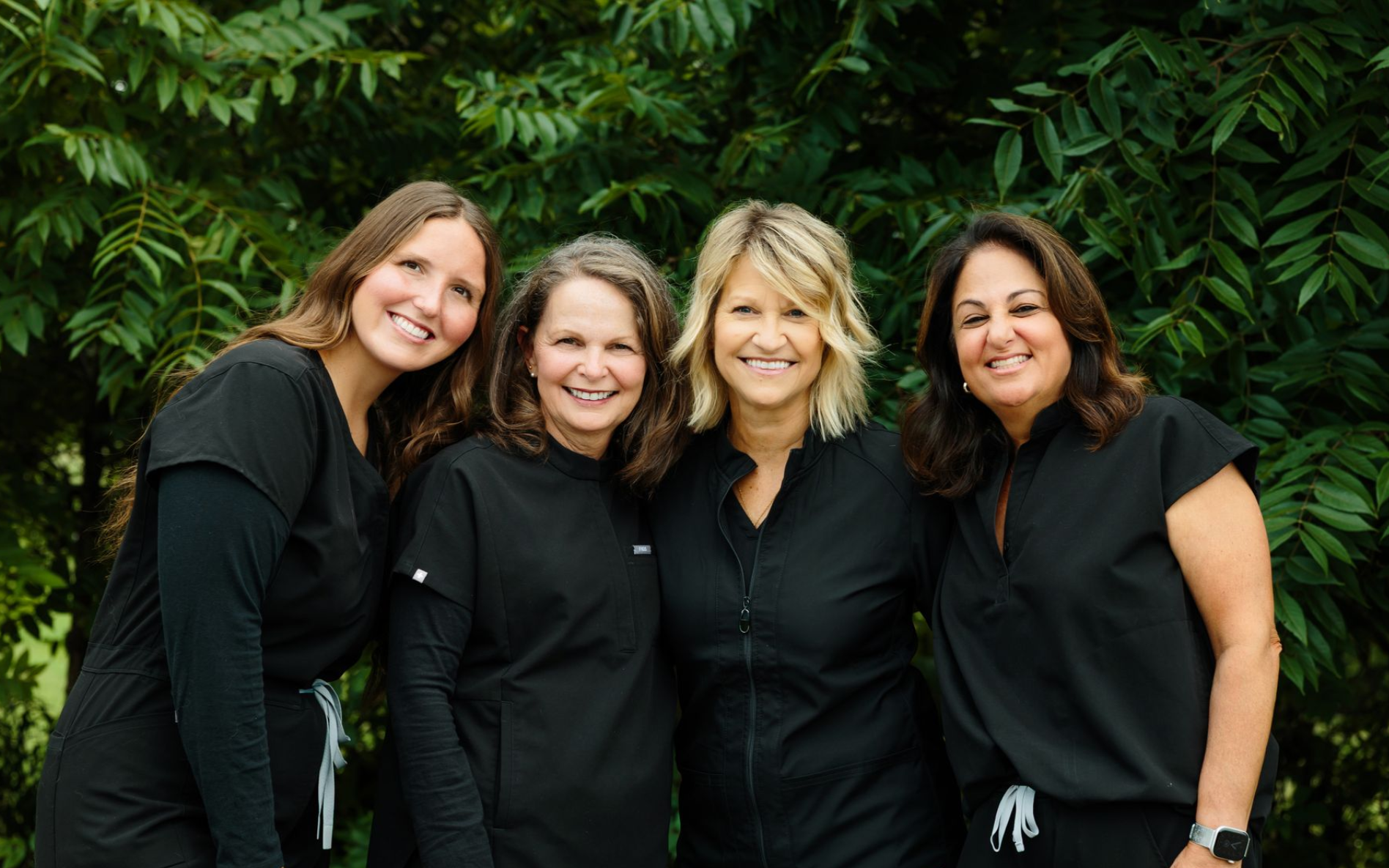 A group five of smiling hygienists in black shirts are posing for a picture.