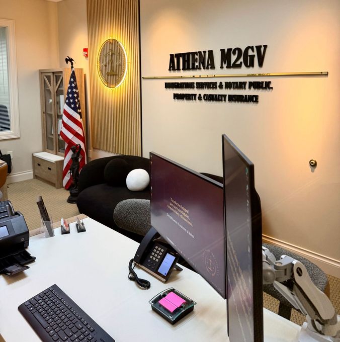 Office interior with desk, dual monitors, keyboard, phone, and American flag. 
