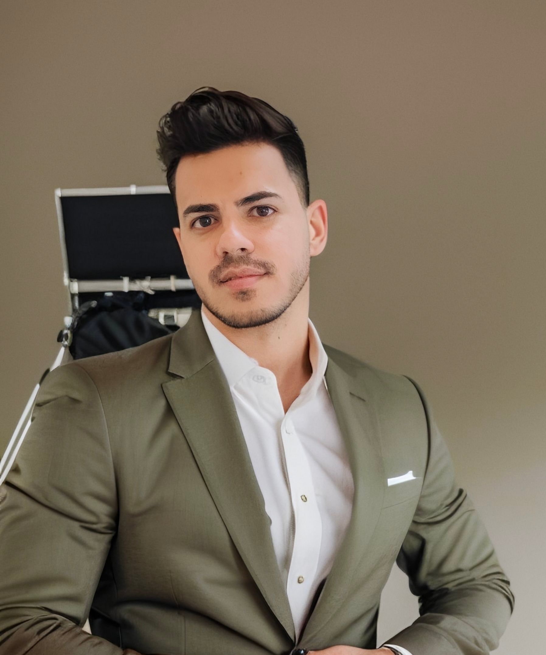 Man in green blazer and white shirt, looking at the camera.