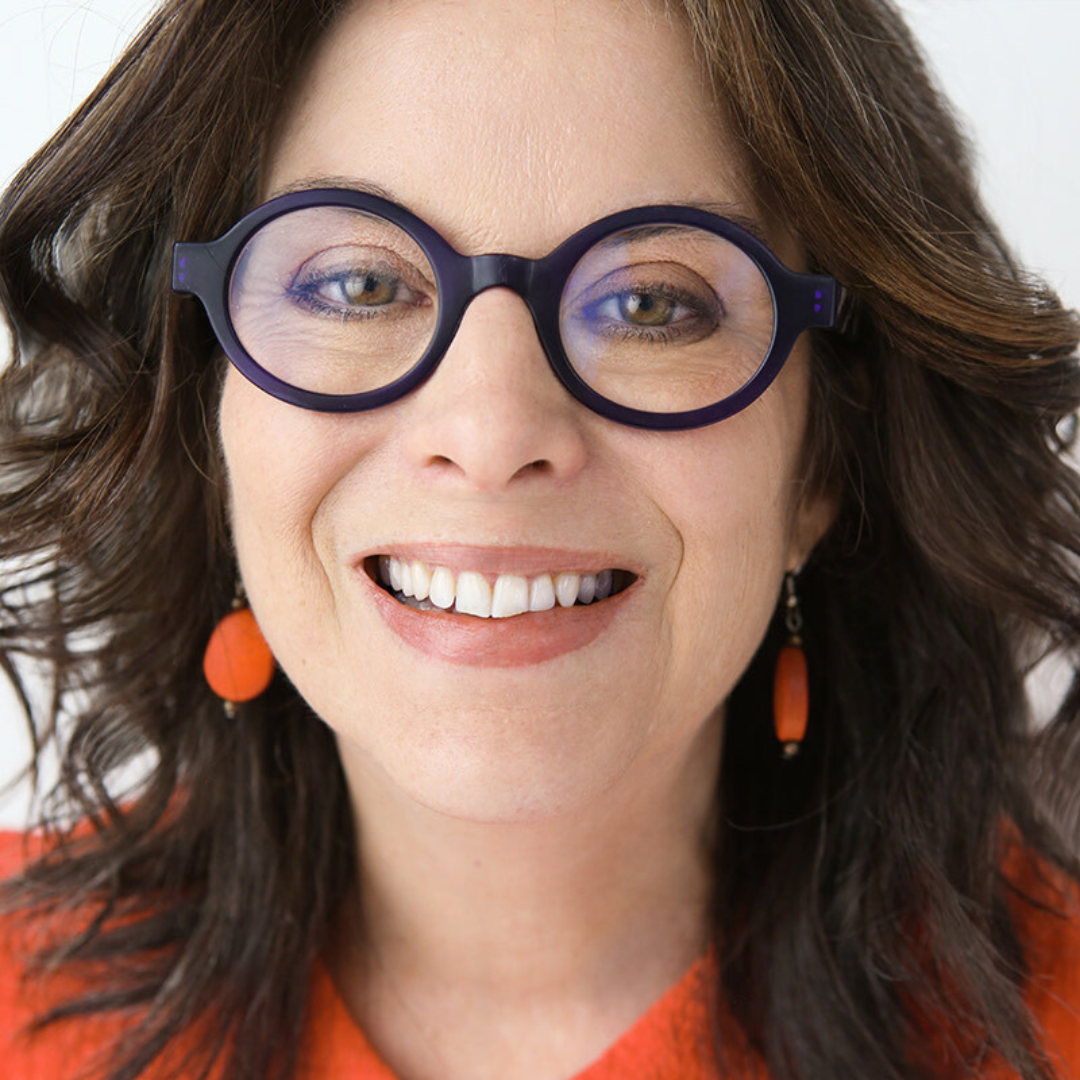 A woman wearing glasses and earrings smiles for the camera