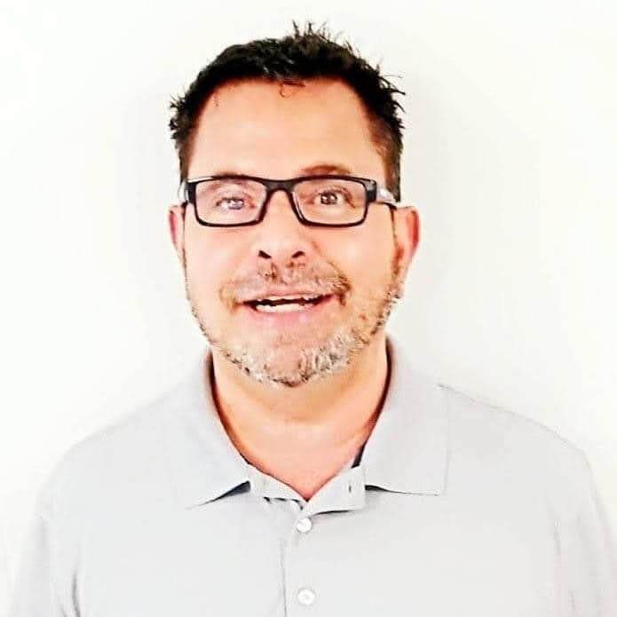 A man with glasses and a beard is smiling for the camera.