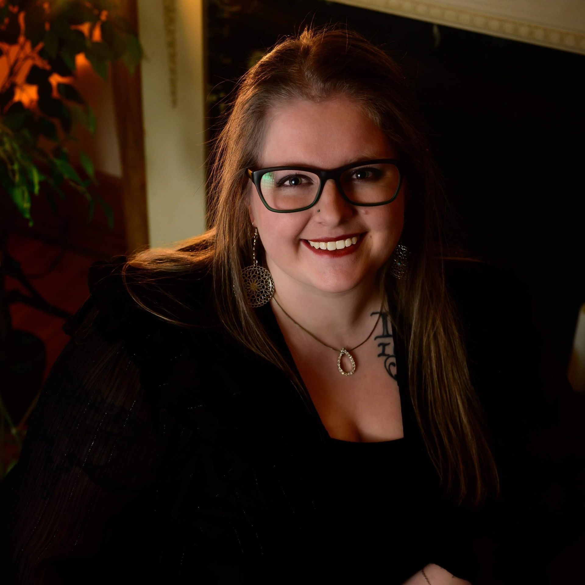 A woman wearing glasses and a necklace is smiling for the camera.