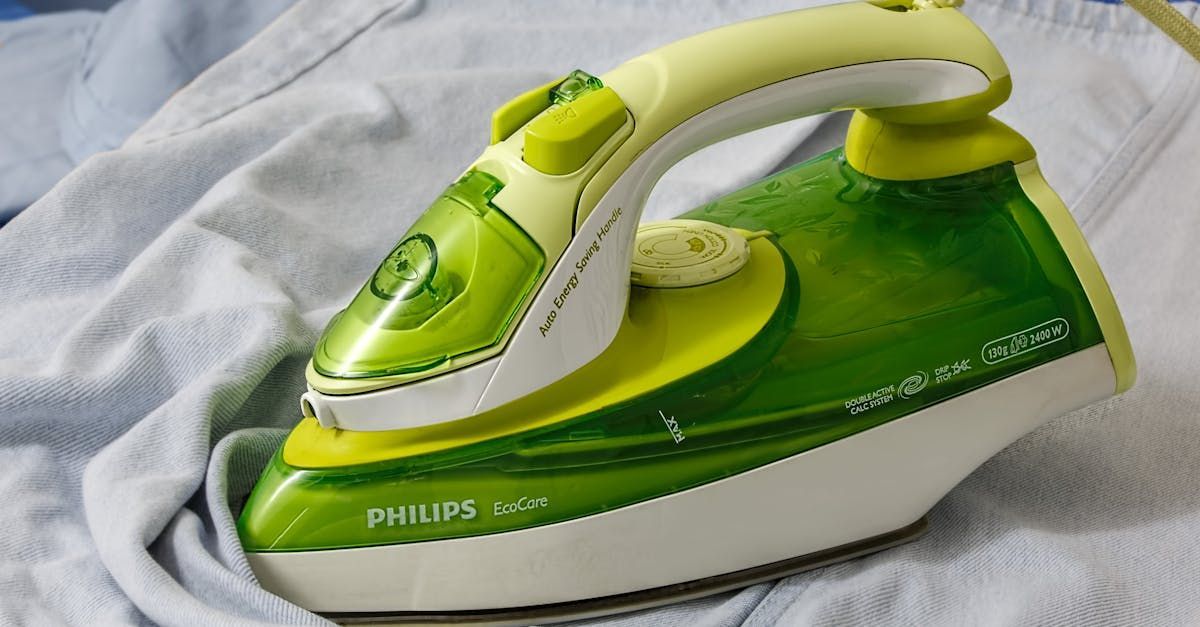 A green and yellow philips iron is sitting on a white shirt.