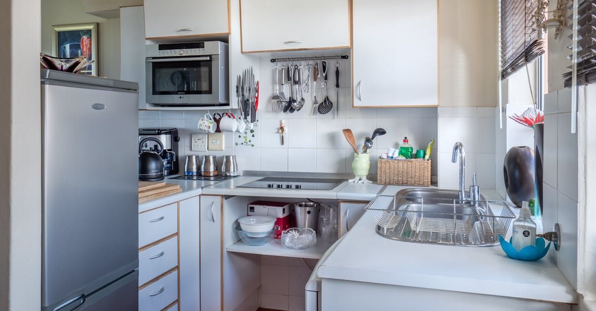 A kitchen with white cabinets , a sink , a refrigerator and a microwave.