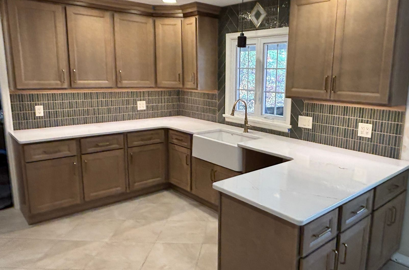 Modern kitchen with light countertops, tan cabinets, and patterned backsplash.