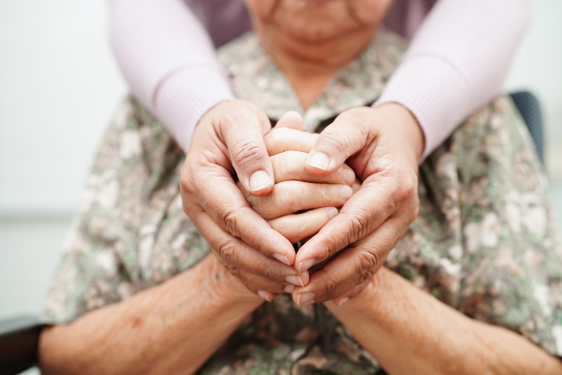 Hands of caregiver holding hands of elderly person, demonstrating care and support.
