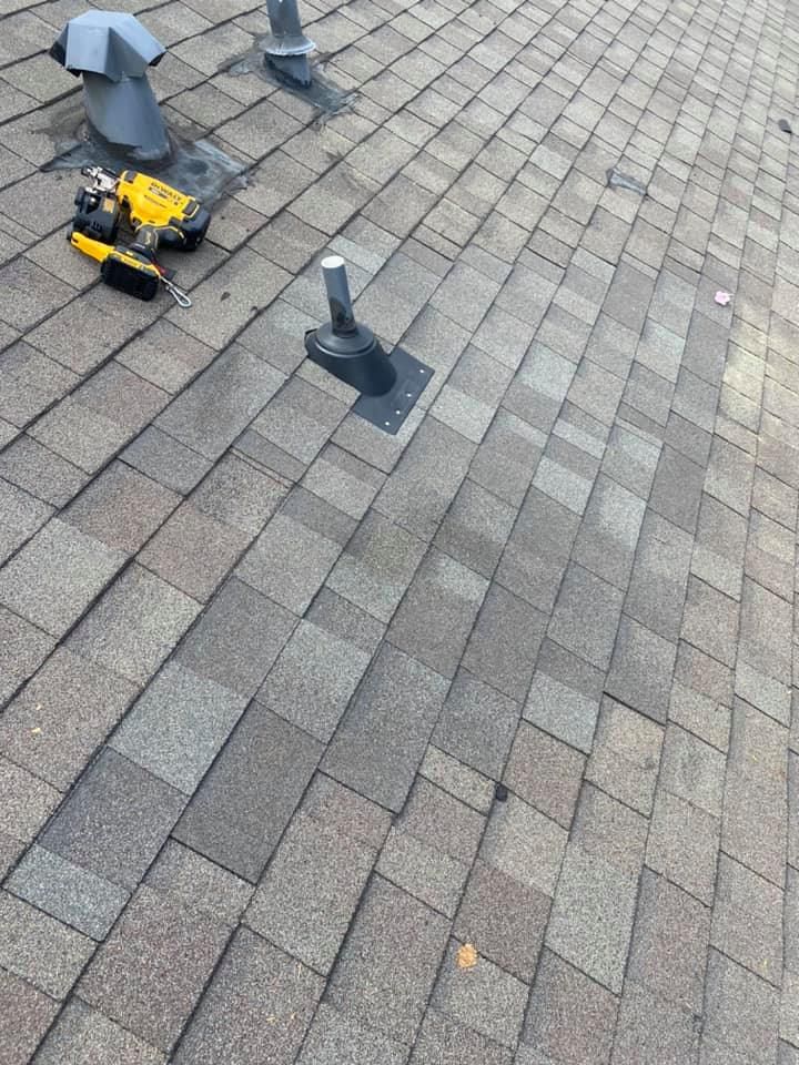 Close-up of asphalt shingle roof. Tool and metal vent on the roof, with discoloration.