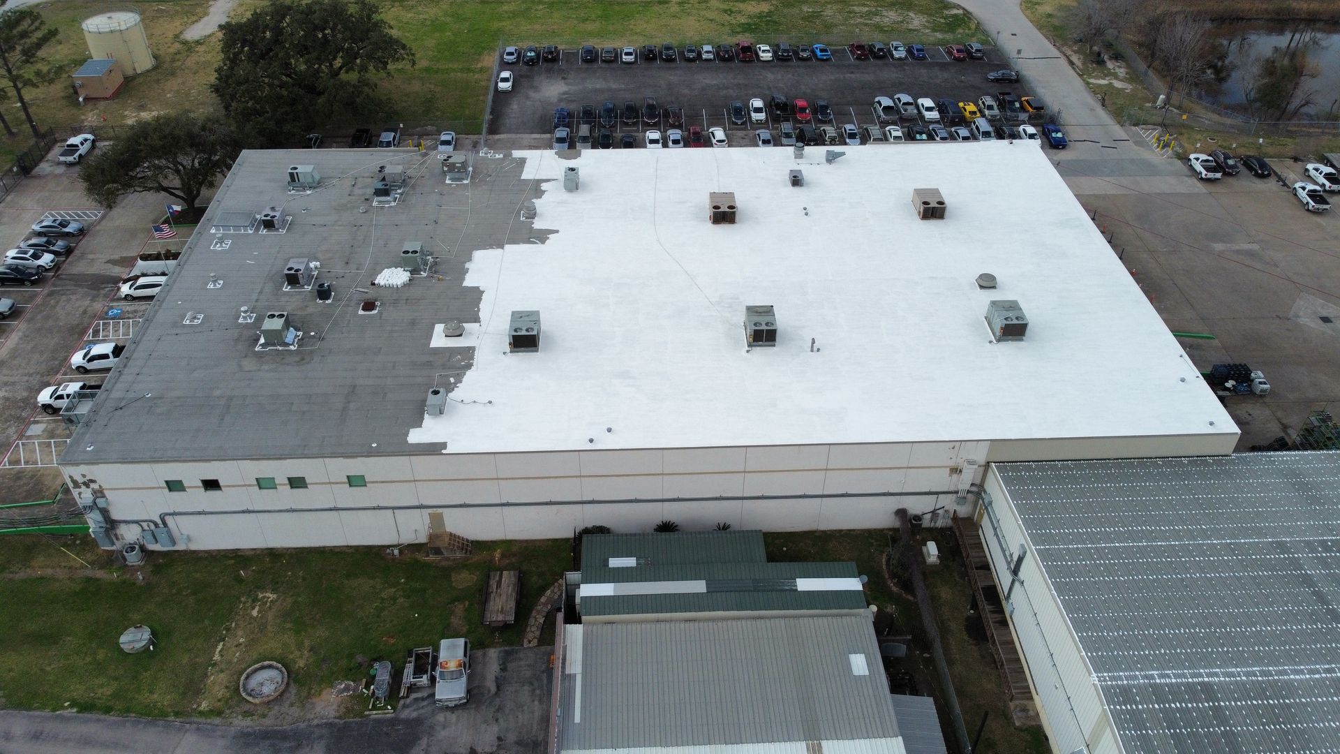 Overhead view of a commercial building with a roof undergoing repair. The roof is partially white and grey.