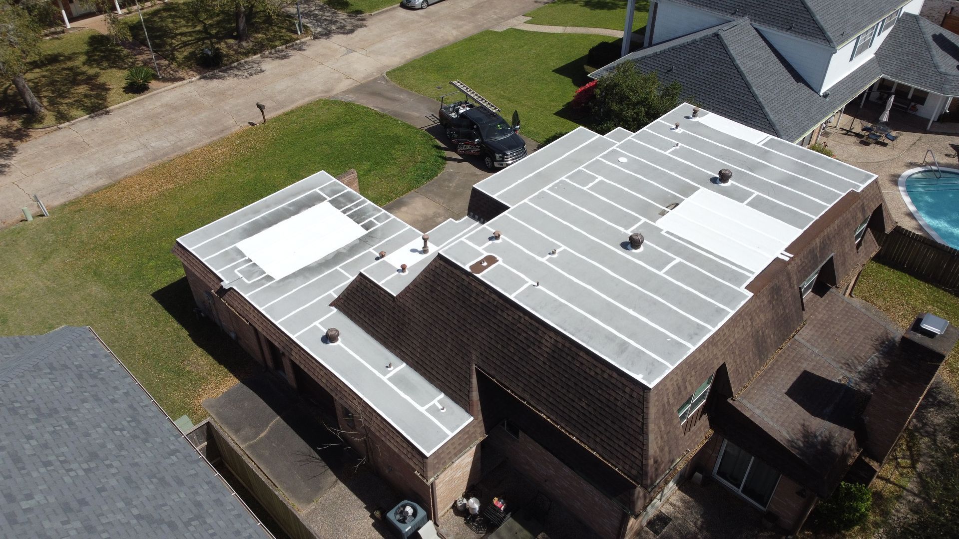 Aerial view of a house with solar panels on the roof and a pool in the backyard.