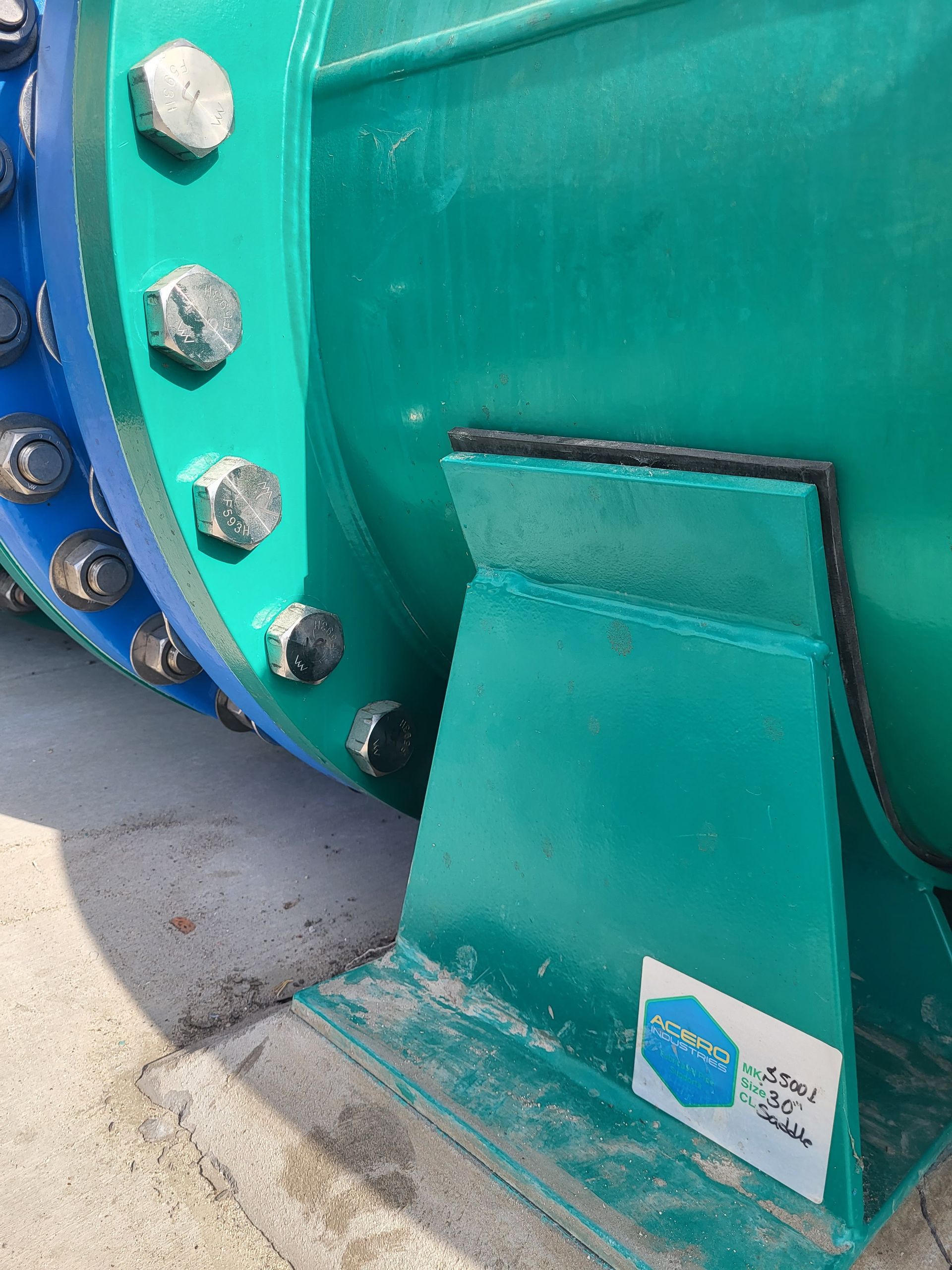  5D Company llc a green pipe with a blue flange is sitting on the ground .