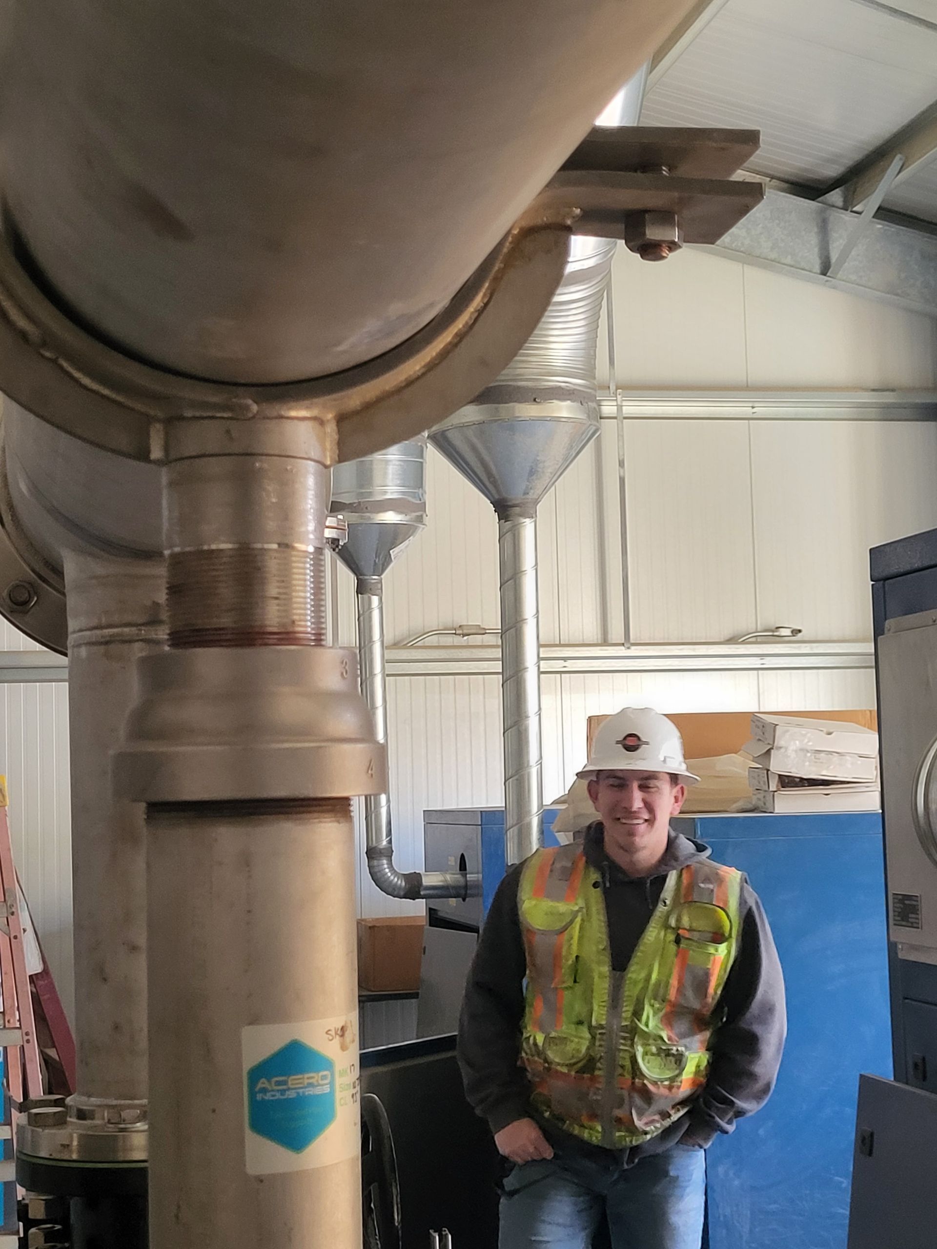  5D Company llc a man in a hard hat and safety vest is standing in front of a large pipe .