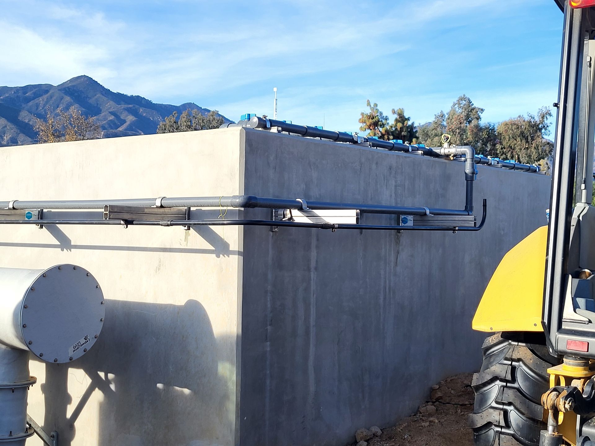  5D Company llc a yellow tractor is parked in front of a concrete wall