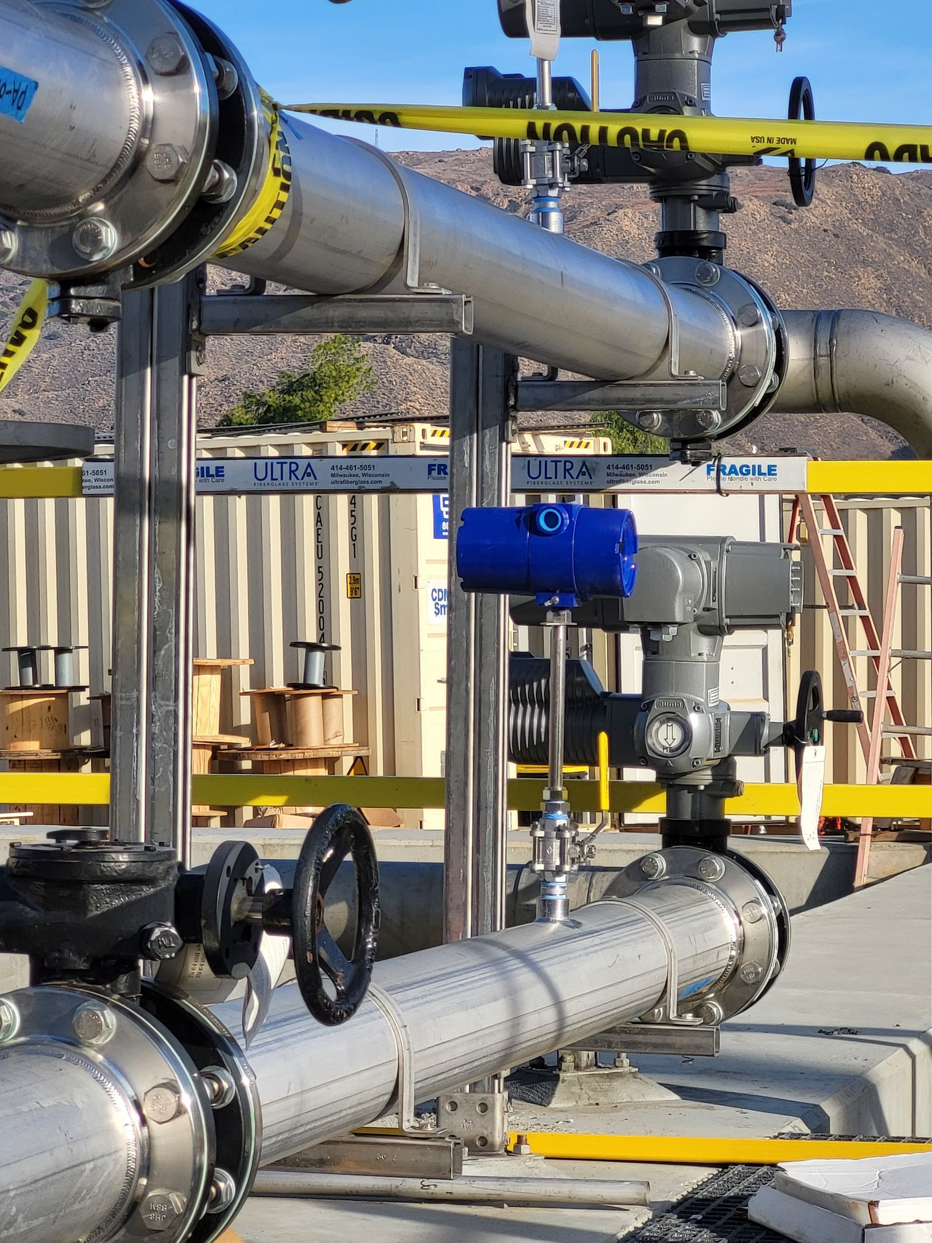  5D Company llc a bunch of pipes and valves with a yellow tape that says caution