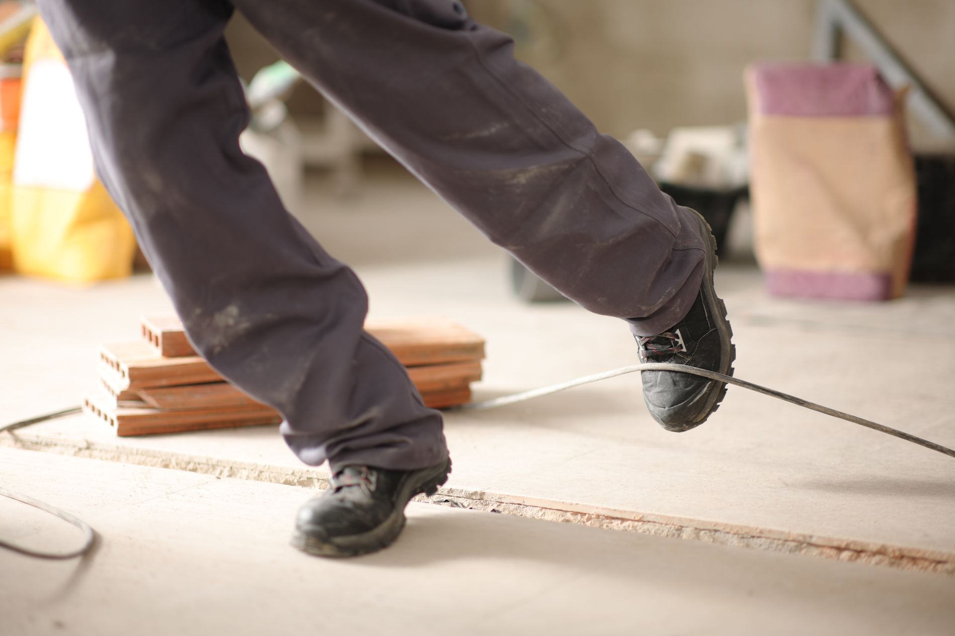 A construction worker stumbling with a cord in a construction site.