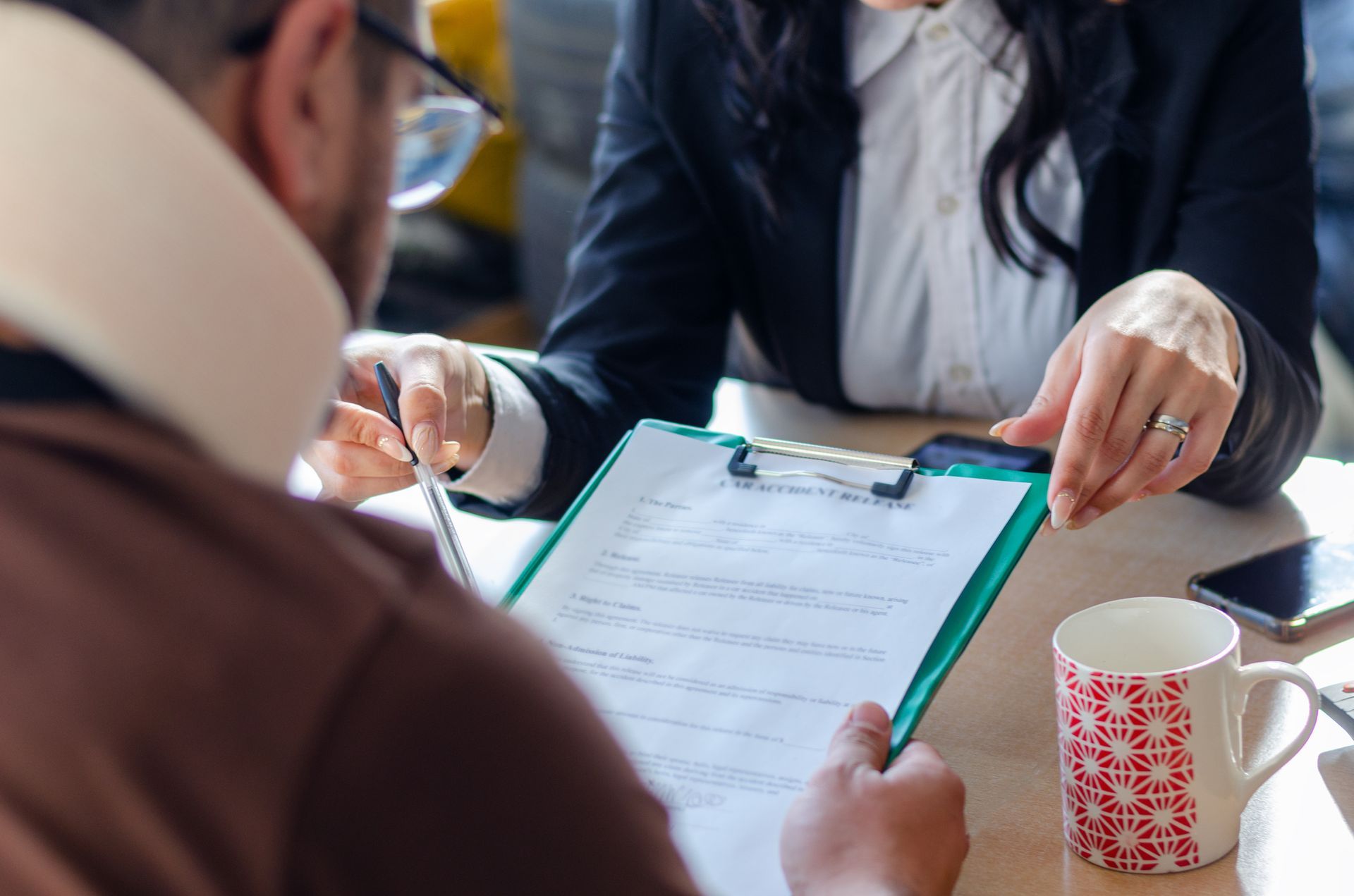 A close-up of an injured man signing a document with a lawyer consulting. A close-up of an injured man signing a document with a lawyer consulting.