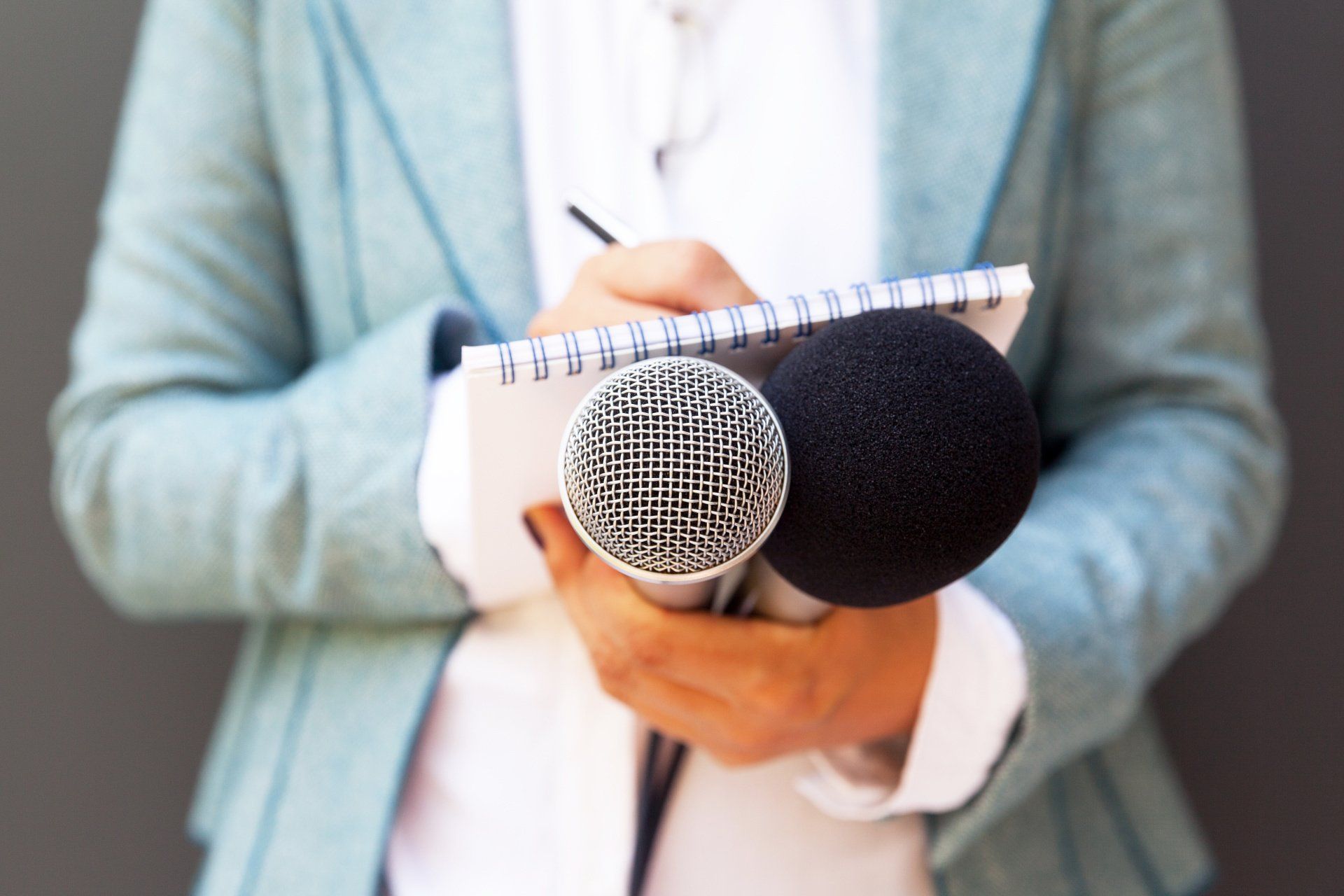 Une femme tient un cahier et un microphone dans ses mains.