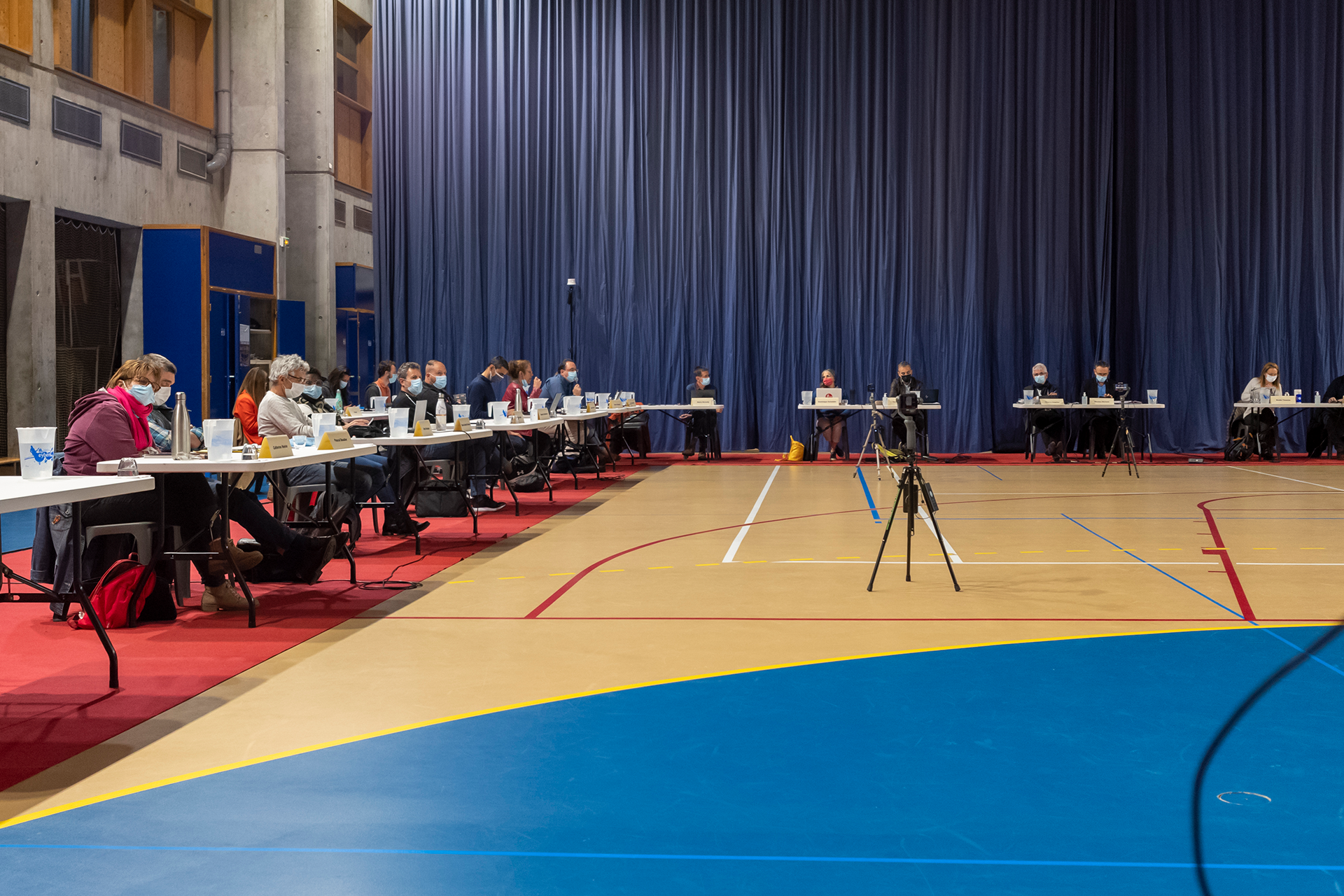 Un groupe de personnes sont assises à des tables dans une salle de sport.