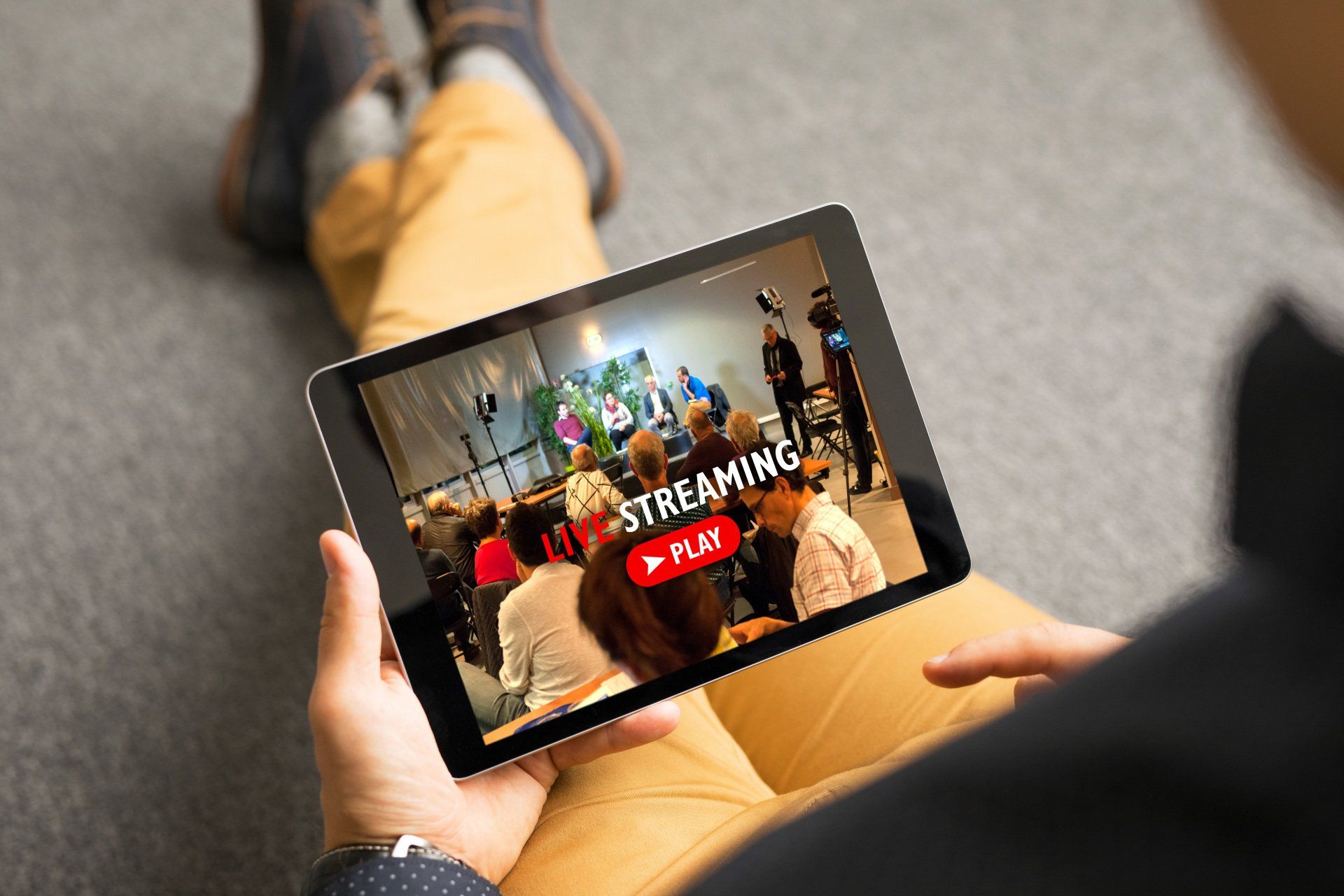 Une personne tient une tablette avec un flux sur l'écran.