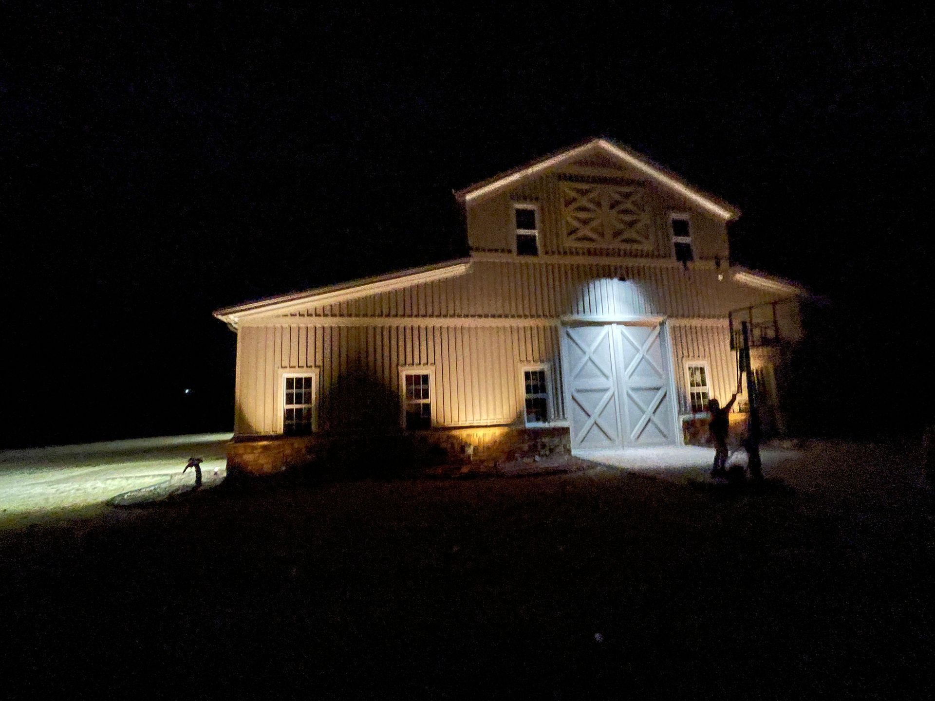 A barn is lit up at night with a lot of lights on it.